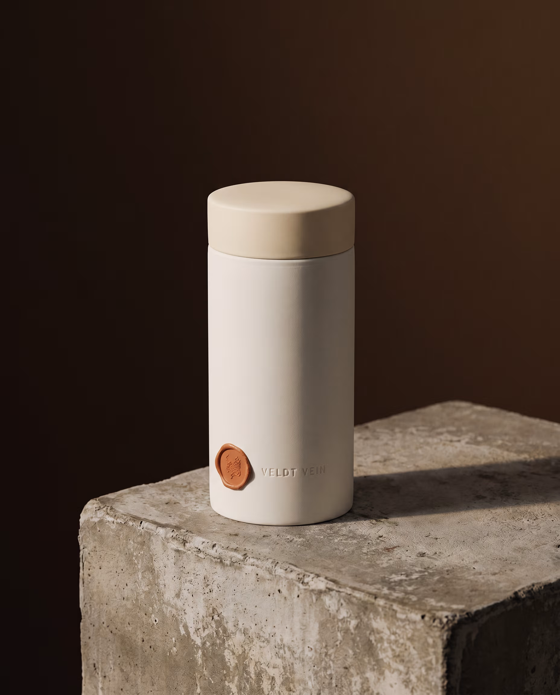 The Karoo Calm 500g porcelain capsule on a concrete plinth — debossed VELDT & VEIN wordmark, terracotta wax seal.