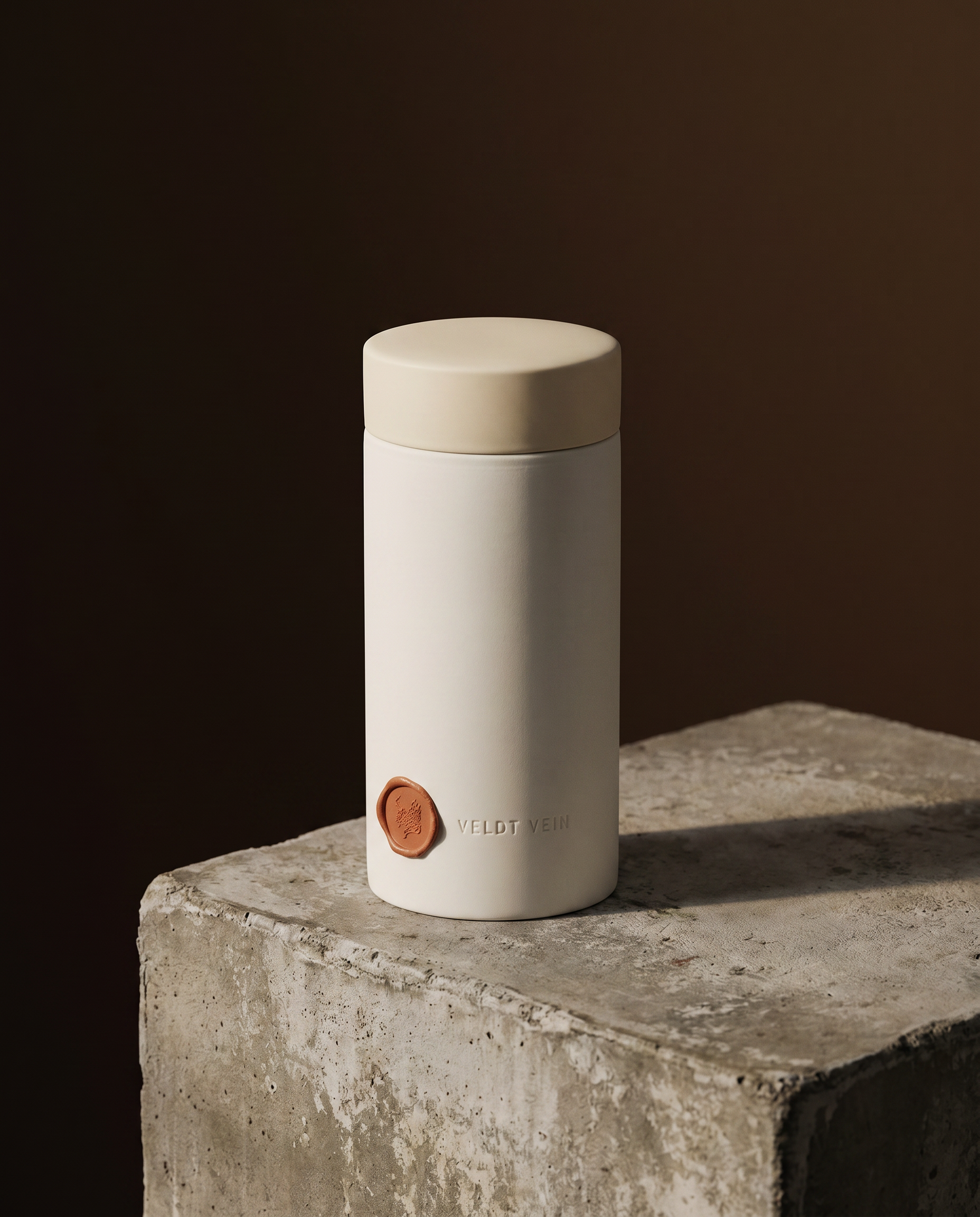 The Karoo Calm 500g porcelain capsule on a concrete plinth — debossed VELDT & VEIN wordmark, terracotta wax seal.