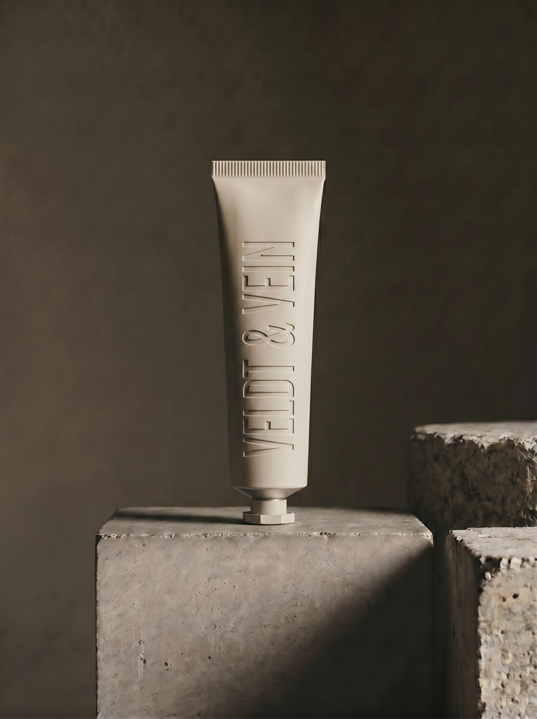 The Marula Peptide Hand & Nail Renewal — debossed aluminium tube on a concrete plinth.